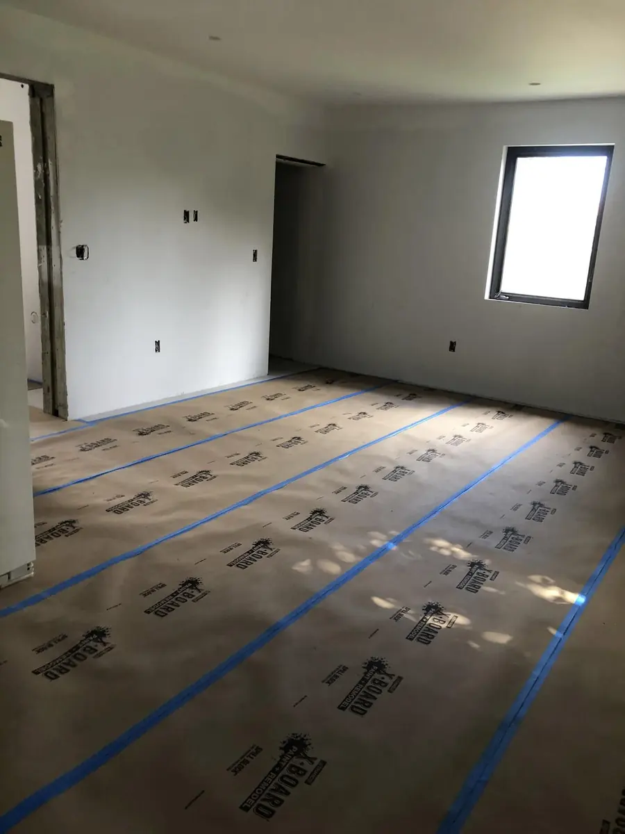 Painted room prepared for finishing, with the entire floor covered in taped protection paper
