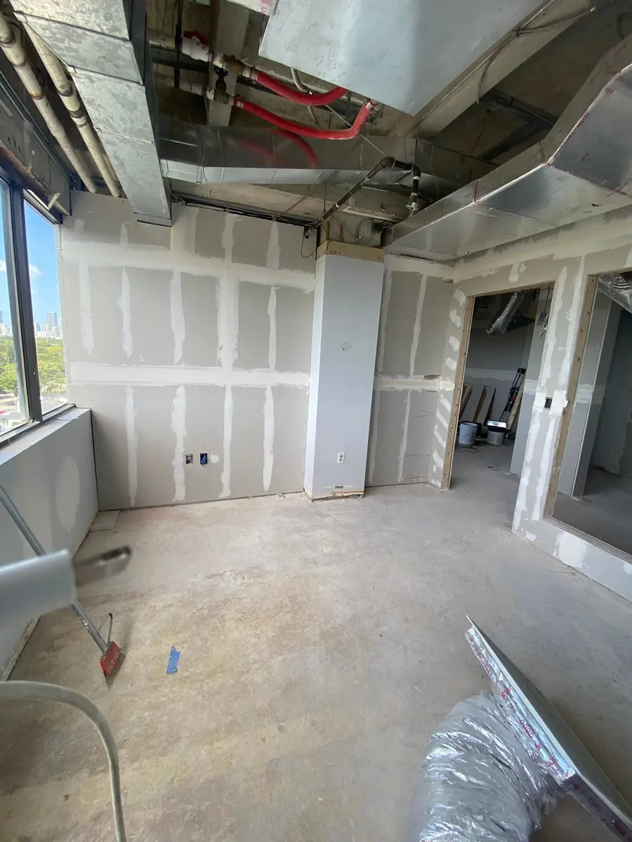 Commercial office with new drywall hung and joints taped and mudded under exposed ductwork