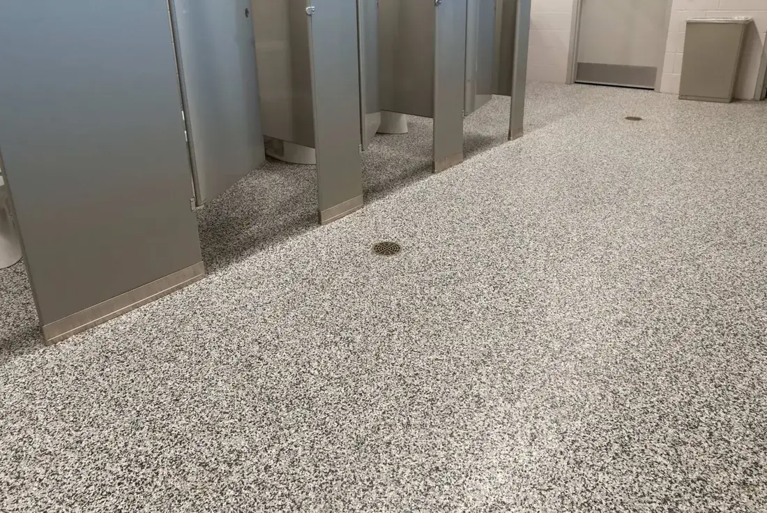 Commercial restroom floor with a gray flake coating around the floor drain