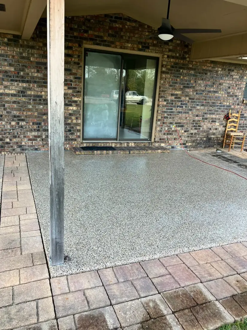 Covered back patio with a beige flake coating bordered by pavers