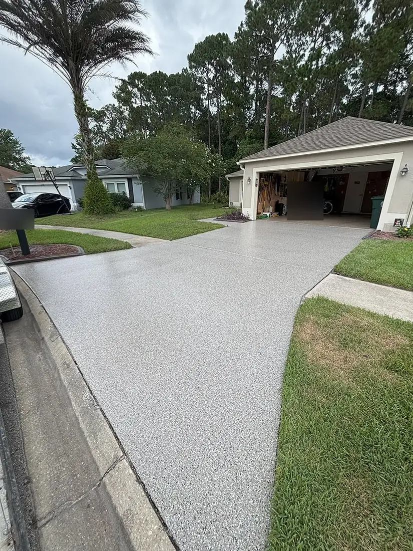 Residential driveway with a light gray flake coating leading to the garage
