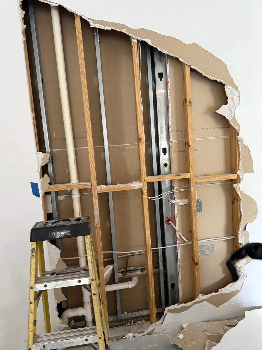 Drywall removed to expose framing, plumbing, and wiring during selective demolition
