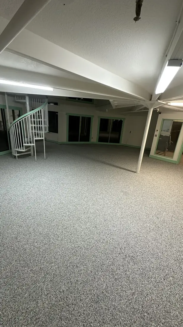 Open interior area with a gray flake floor coating and a spiral staircase