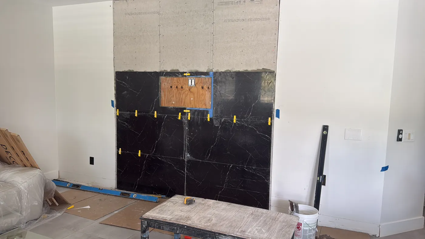 Cement backer board and 24 x 48 inch black marble-look porcelain tiles being set with a leveling system