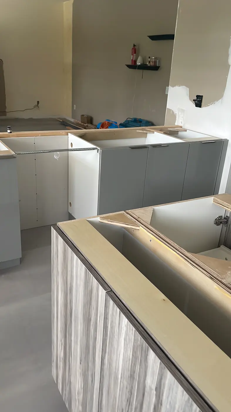 Modern gray high-gloss base cabinets installed, with a wood-grain island in the foreground