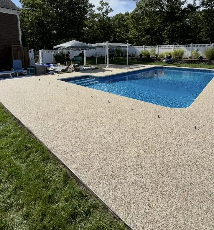 Pool deck finished with a sand-tone flake coating around an in-ground pool