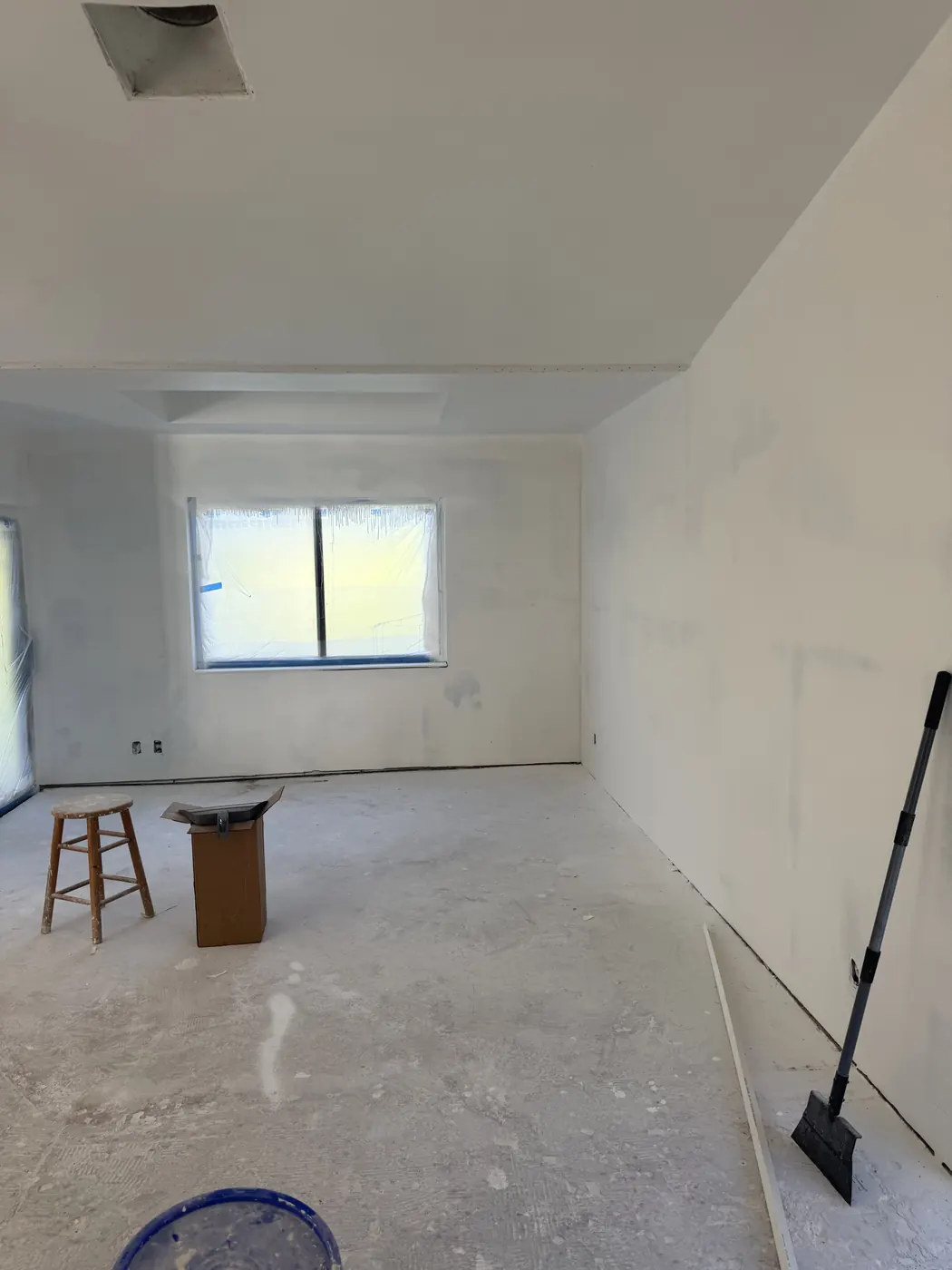 Bedroom with new drywall finished and primed, window masked, ready for paint and new flooring