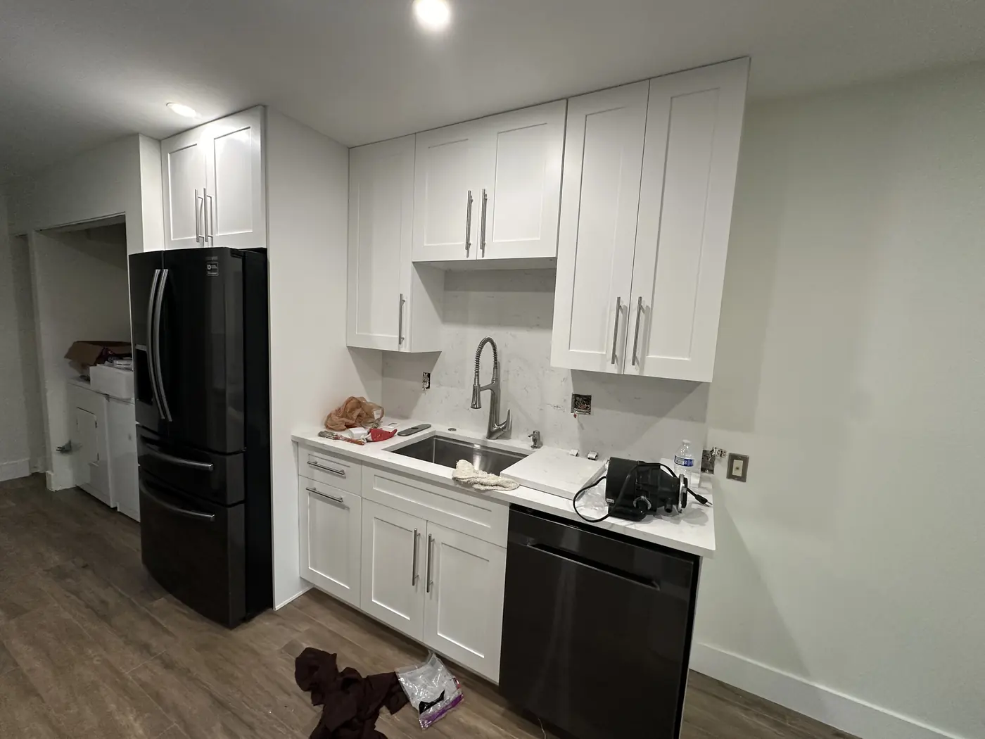 Sink wall with white shaker cabinets, quartz countertop and full-height quartz backsplash