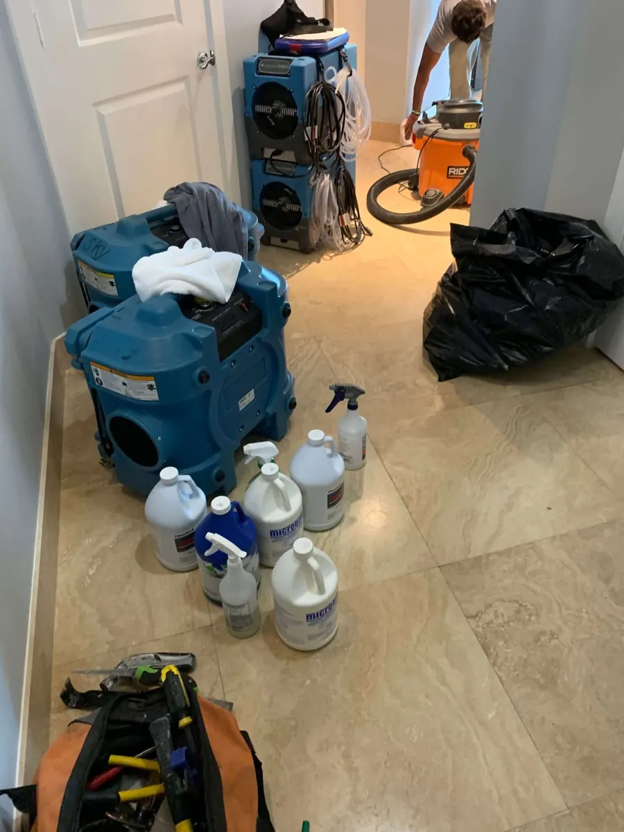 Water mitigation setup in a hallway with air scrubbers, stacked dehumidifiers, a wet vac and antimicrobial products