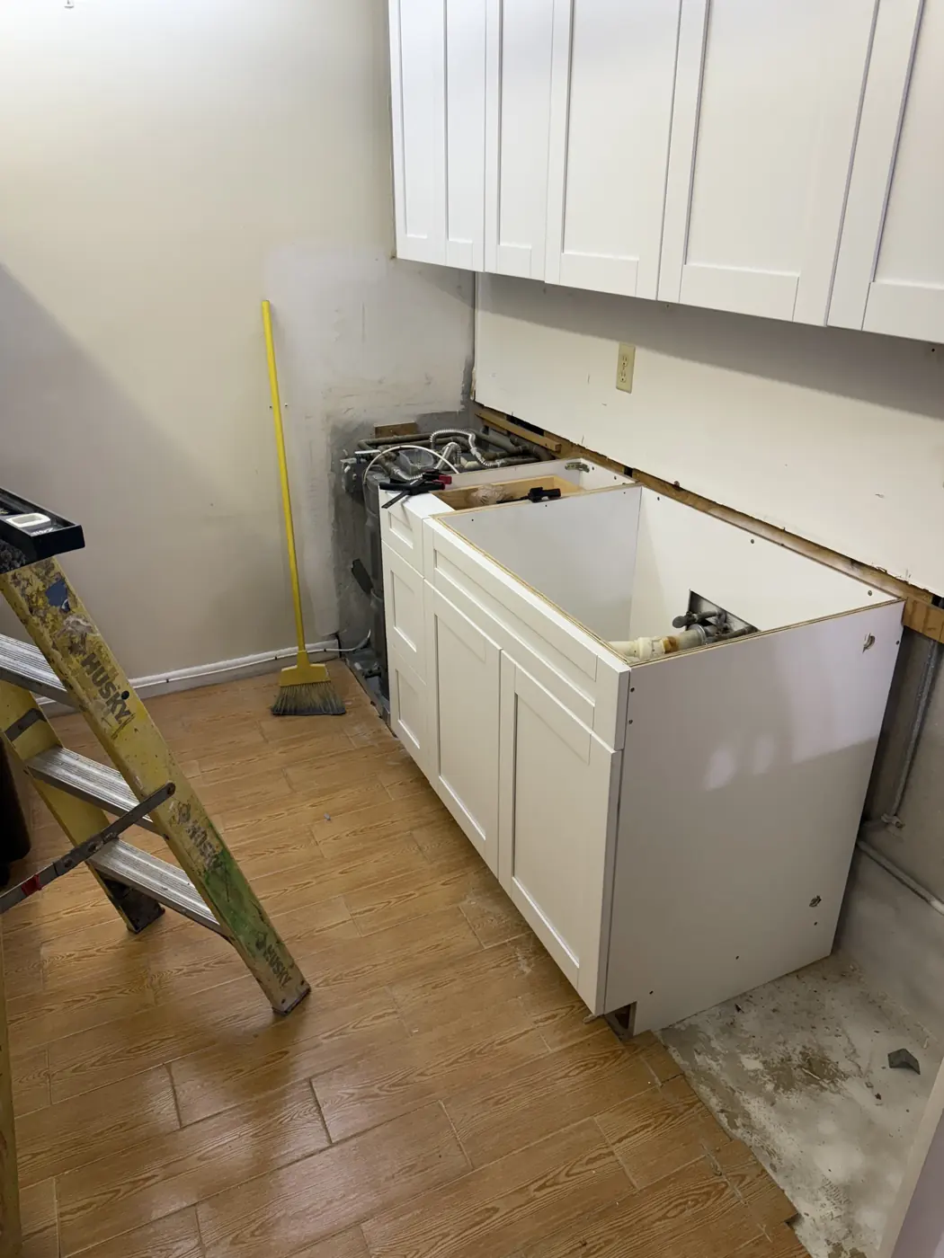 White shaker sink base and wall cabinets being installed in a small room